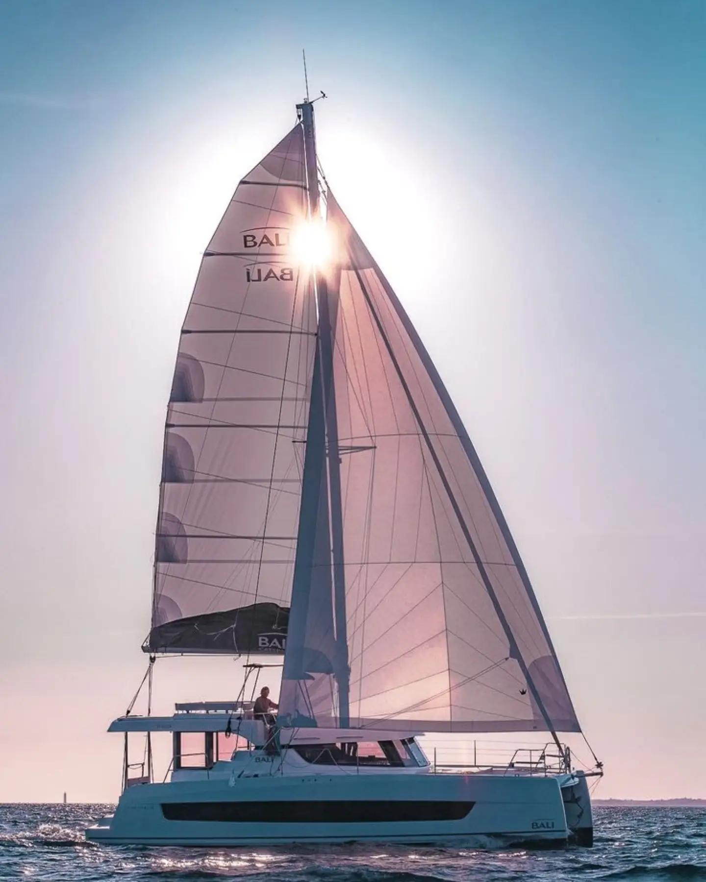 A Bali catamaran of the Locke’s type under full sail at golden hour