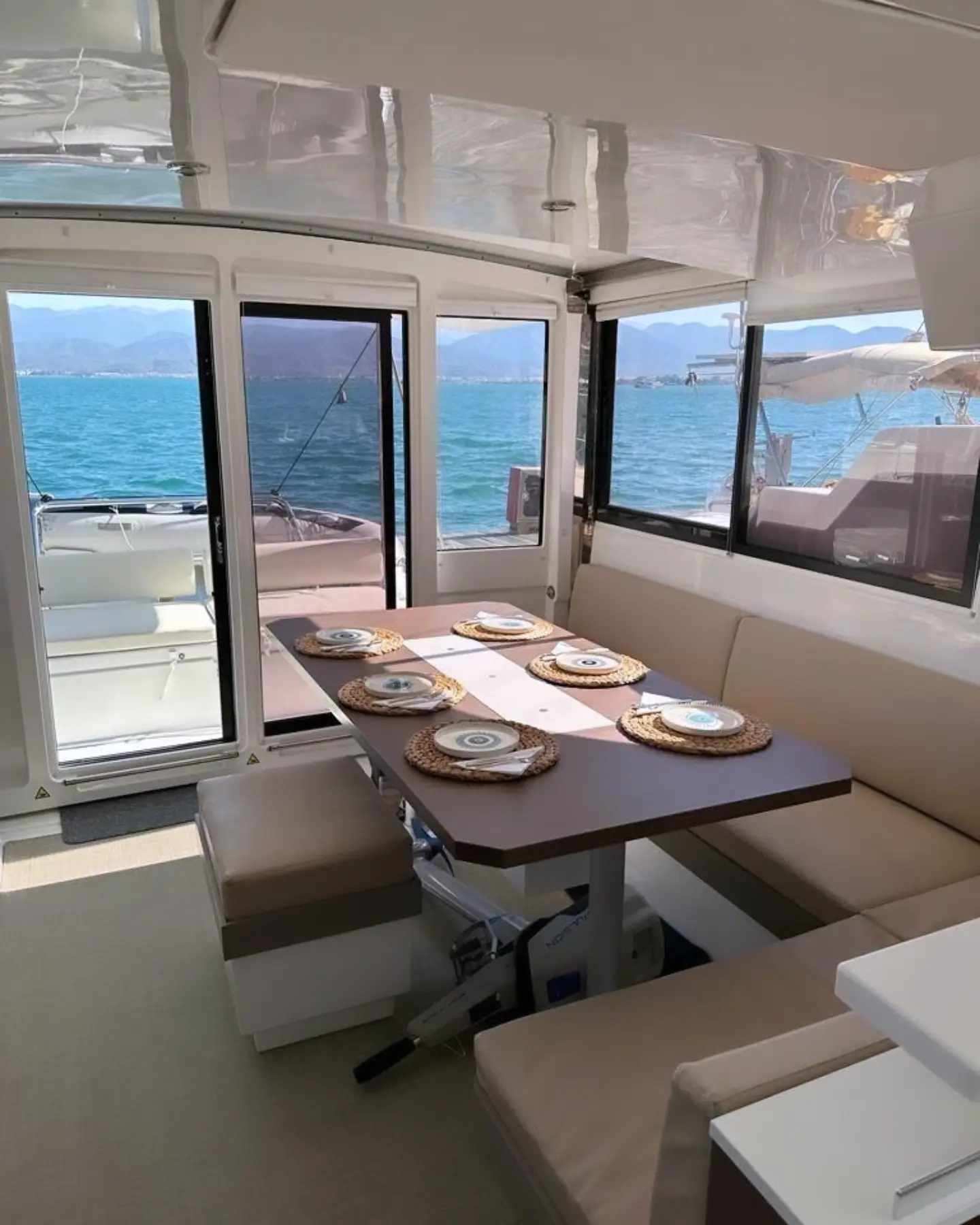 Catamaran saloon with dining table set for six and sea views all round