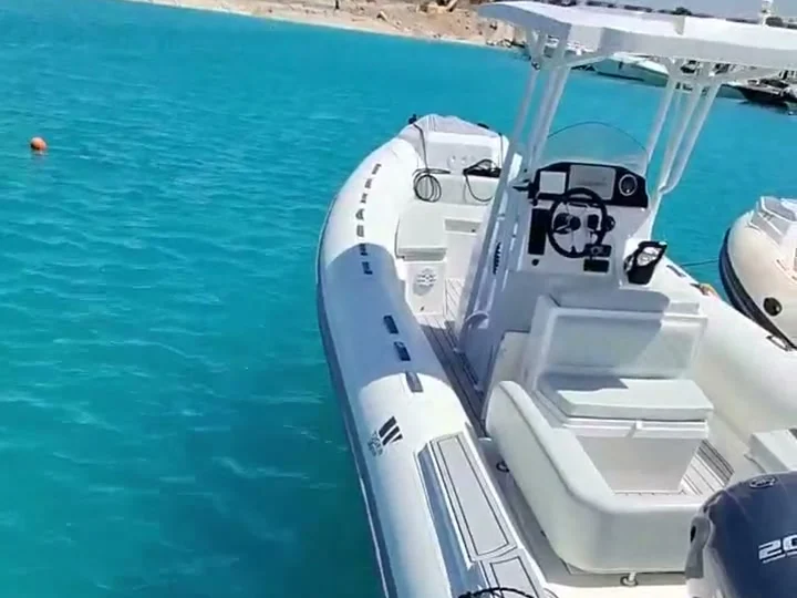 The private speedboat, a RIB with a shaded T-top console, moored on bright turquoise water